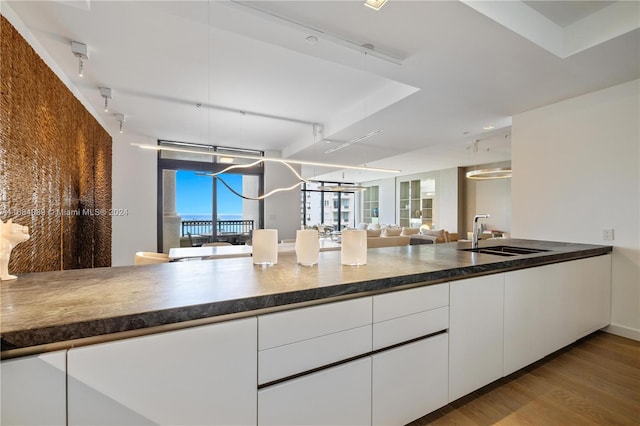 kitchen with white cabinets, light hardwood / wood-style floors, and sink