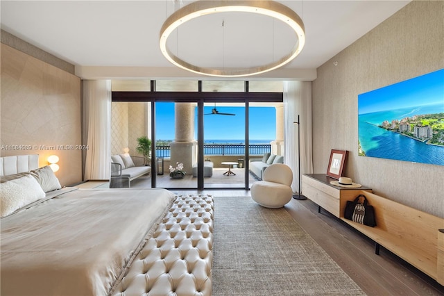 bedroom featuring a water view, hardwood / wood-style floors, floor to ceiling windows, and access to exterior