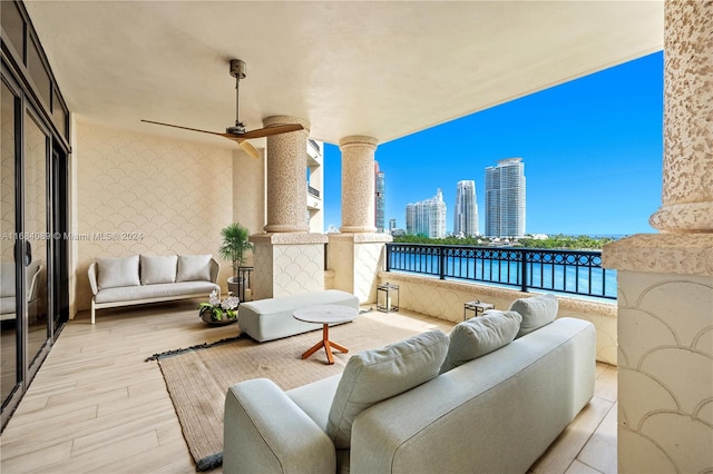 balcony with a water view, ceiling fan, and an outdoor living space