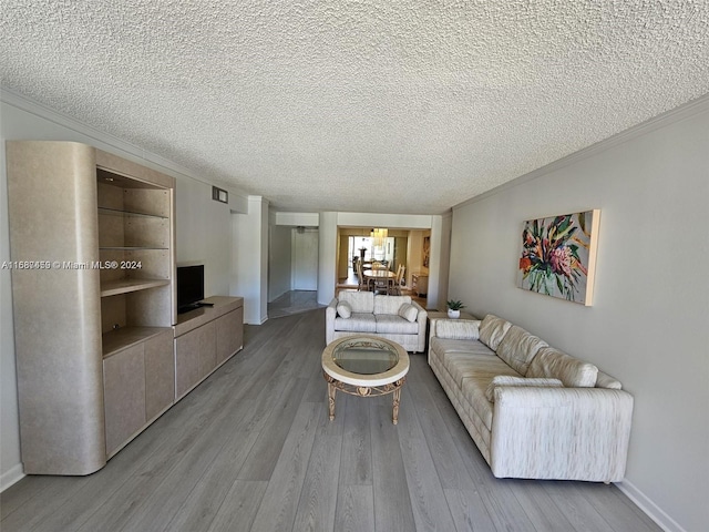 unfurnished living room featuring a textured ceiling, light wood-type flooring, and crown molding