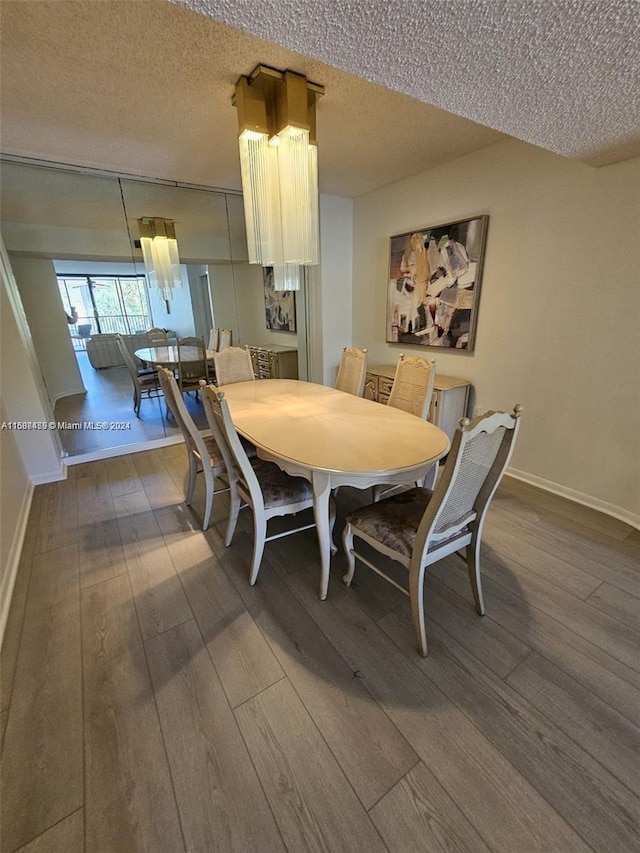 dining space featuring wood-type flooring and a textured ceiling