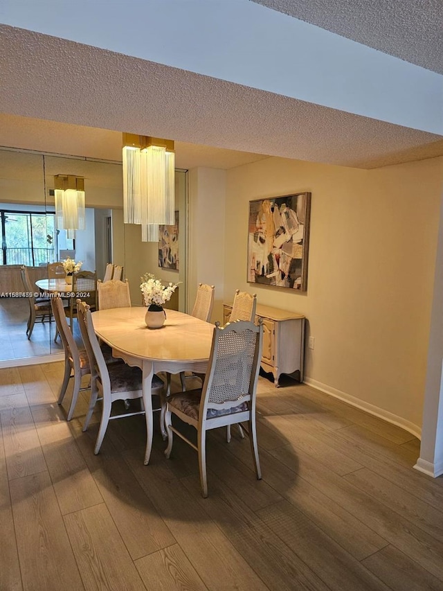 dining area with wood-type flooring and a textured ceiling