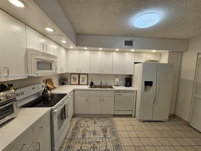 kitchen with white cabinets, sink, white appliances, and light tile patterned floors