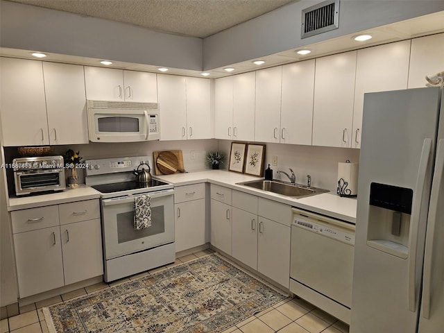 kitchen featuring light tile patterned floors, white appliances, a textured ceiling, and sink