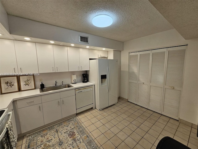 kitchen with white cabinets, light tile patterned floors, and white appliances