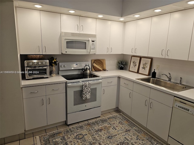 kitchen featuring white appliances, sink, light tile patterned floors, and white cabinets