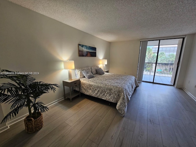 bedroom with a textured ceiling, hardwood / wood-style flooring, and access to exterior