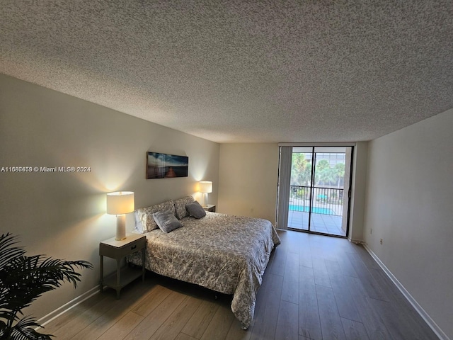 bedroom featuring hardwood / wood-style floors, a textured ceiling, and access to outside