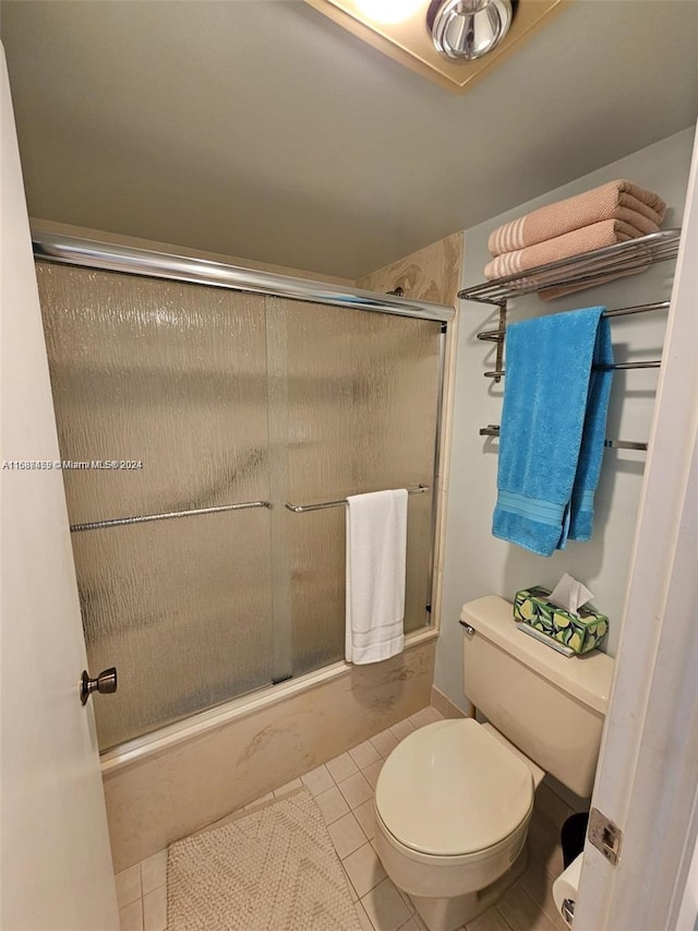 bathroom with a shower with door, tile patterned flooring, and toilet