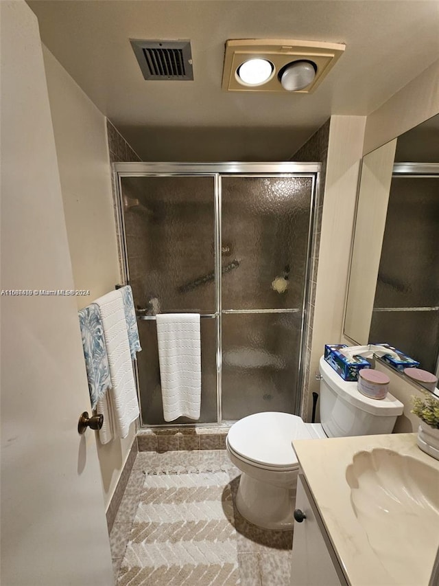 bathroom with toilet, vanity, tile patterned flooring, and walk in shower