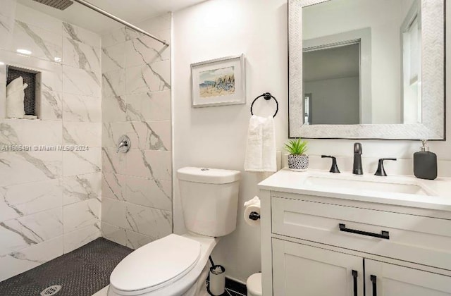 bathroom featuring vanity, toilet, and tiled shower