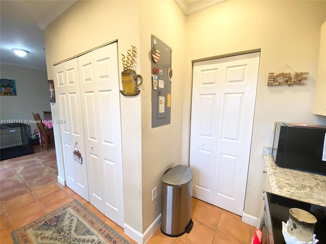 hallway with light tile patterned floors and crown molding