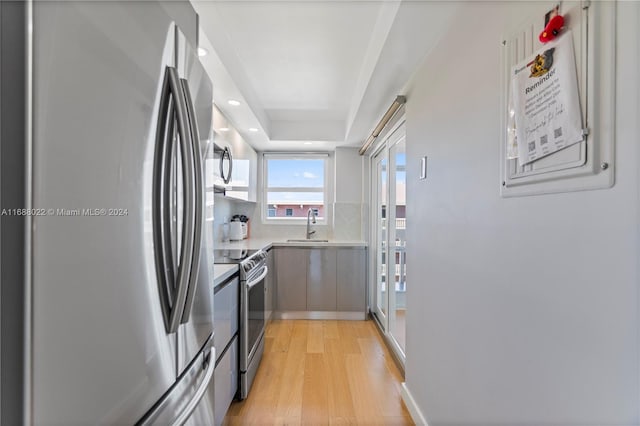 180 NE 12th Ave Unit 12E, Hallandale Beach, FL 33009 - kitchen featuring appliances with stainless steel finishes, light wood-style floors, light countertops, a sink, and backsplash
