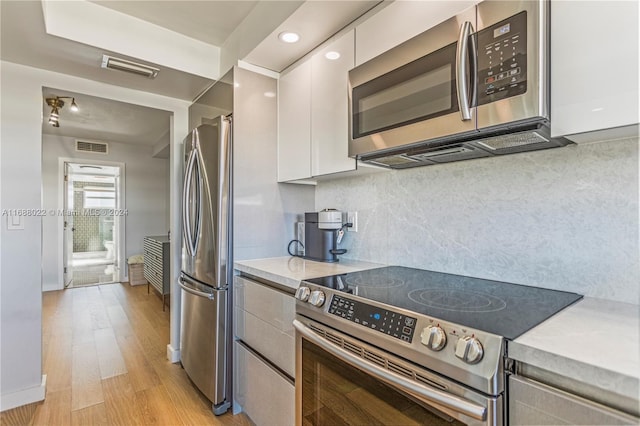 180 NE 12th Ave Unit 12E, Hallandale Beach, FL 33009 - kitchen with appliances with stainless steel finishes, white cabinets, light countertops, light wood-type flooring, and tasteful backsplash