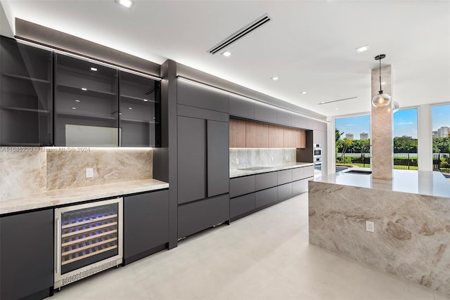 kitchen with beverage cooler, pendant lighting, decorative backsplash, and light stone countertops