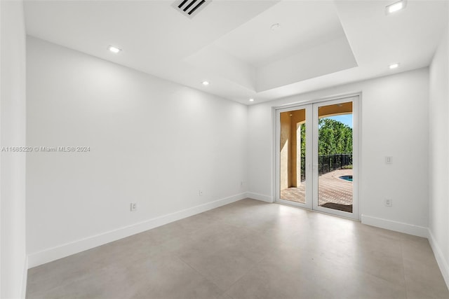 empty room with french doors and a raised ceiling