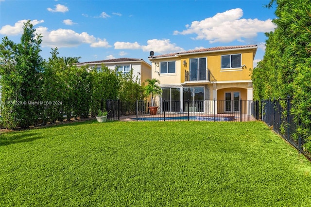 rear view of house with a fenced in pool and a lawn