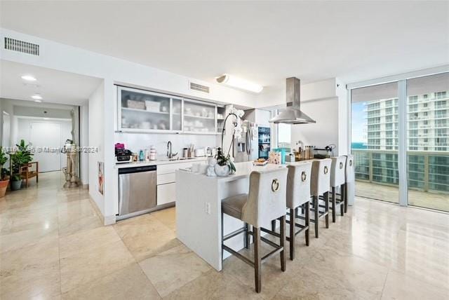 kitchen featuring white cabinets, a kitchen bar, island exhaust hood, and stainless steel appliances