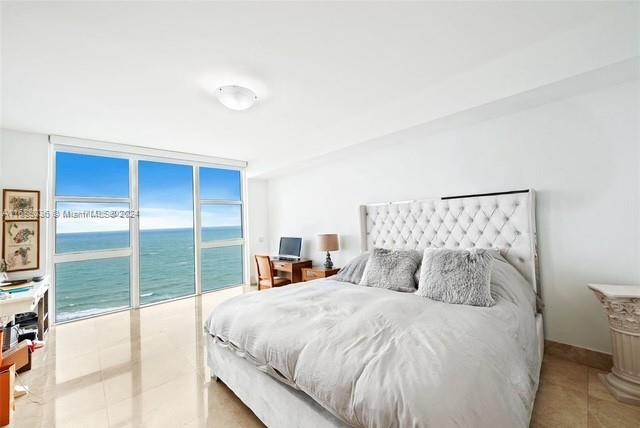 bedroom with access to outside, floor to ceiling windows, and light tile patterned floors