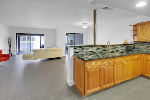 kitchen featuring tile patterned floors, sink, tasteful backsplash, and dark stone countertops