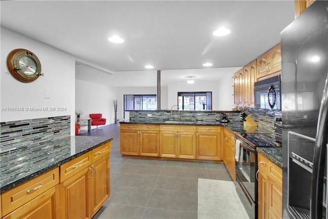 kitchen with kitchen peninsula, black appliances, sink, and dark stone counters