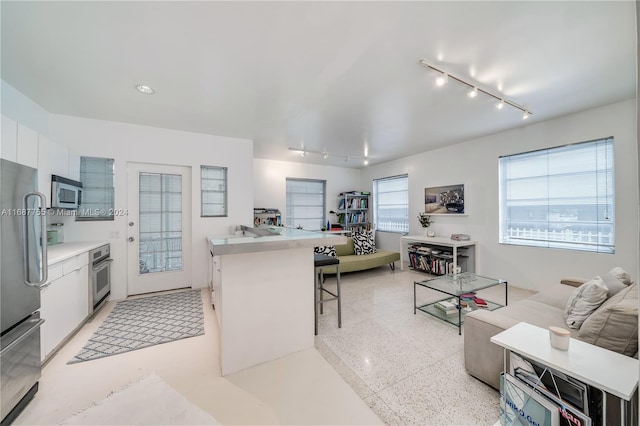 kitchen featuring white cabinetry, appliances with stainless steel finishes, a kitchen breakfast bar, and rail lighting