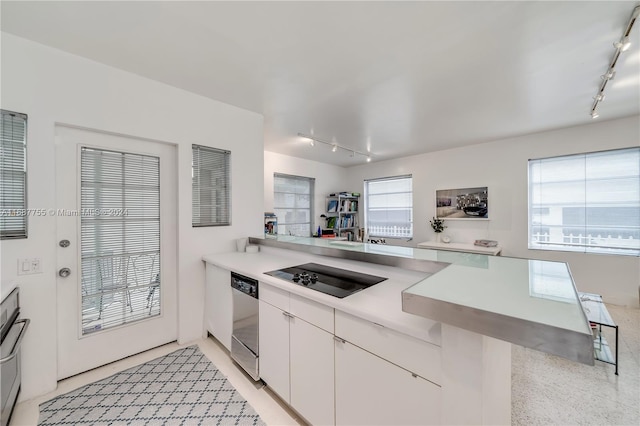 kitchen featuring black electric cooktop, white cabinets, kitchen peninsula, track lighting, and stainless steel dishwasher