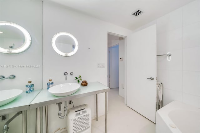 bathroom with tile walls, vanity, and a bathing tub