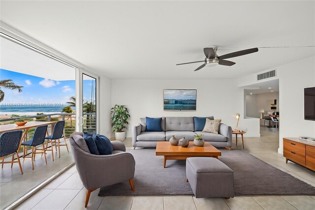 tiled living room featuring a water view and ceiling fan