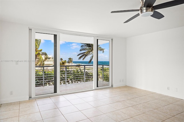 spare room featuring a water view, light tile patterned floors, and ceiling fan