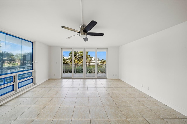 spare room with expansive windows, ceiling fan, and light tile patterned floors