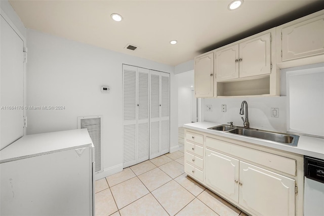 kitchen featuring dishwasher, sink, white cabinets, and light tile patterned floors