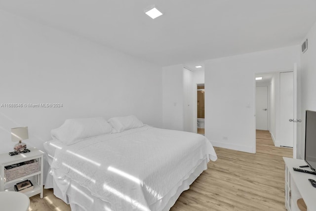 bedroom with ensuite bathroom and light hardwood / wood-style flooring