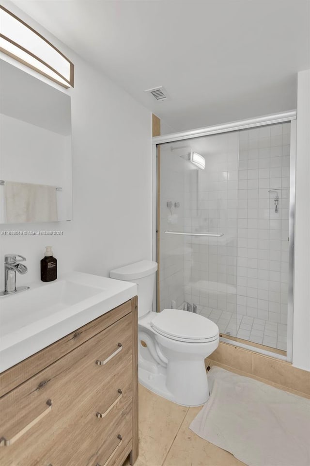 bathroom with vanity, tile patterned floors, toilet, and a shower with shower door