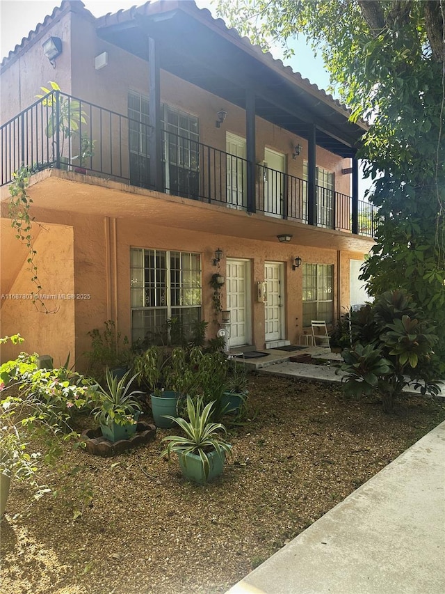 view of front of property featuring a balcony, a patio area, and stucco siding