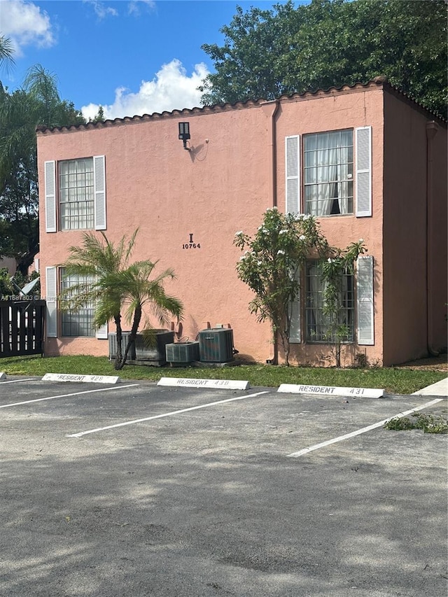 view of property exterior featuring uncovered parking, central AC unit, and stucco siding