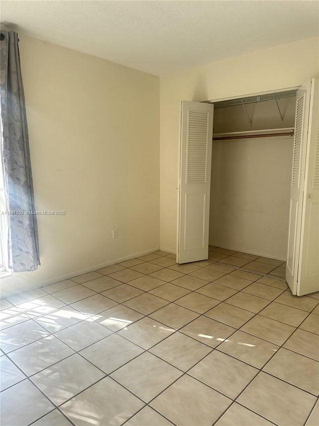 unfurnished bedroom with light tile patterned floors and a closet