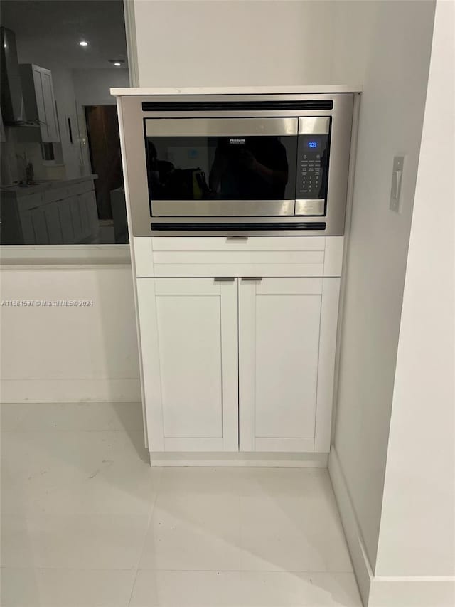 1201 Marseille Dr Unit 17, Miami Beach, FL 33141 - detailed view of stainless steel microwave, extractor fan, white cabinets, and baseboards