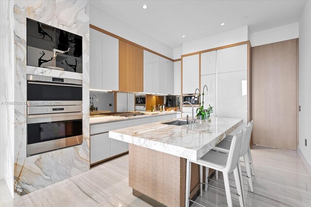2811 S Bayshore Dr Unit 4C, Miami, FL 33133 - kitchen featuring stainless steel appliances, a sink, a center island with sink, recessed lighting, and a kitchen breakfast bar