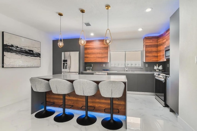 kitchen featuring sink, appliances with stainless steel finishes, a kitchen bar, decorative light fixtures, and a center island