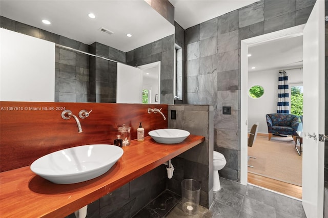 bathroom featuring toilet, vanity, tile walls, and walk in shower