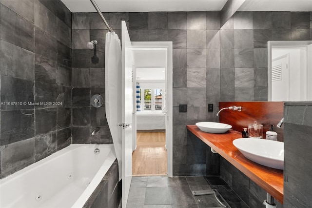 bathroom with hardwood / wood-style floors, sink, tile walls, and shower / tub combo