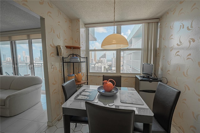 tiled dining area featuring a wealth of natural light, a textured ceiling, and floor to ceiling windows