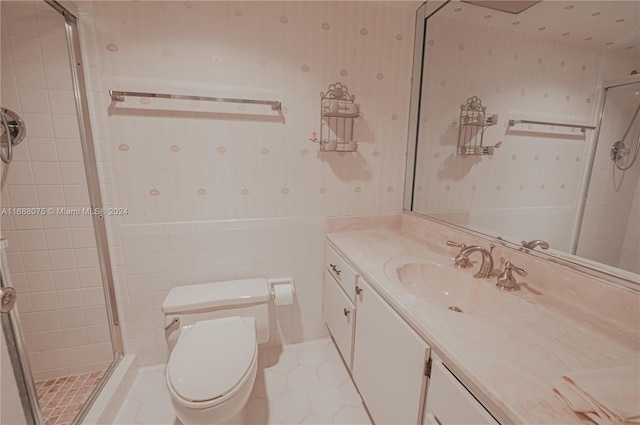 bathroom featuring tile patterned flooring, vanity, toilet, and a shower with door