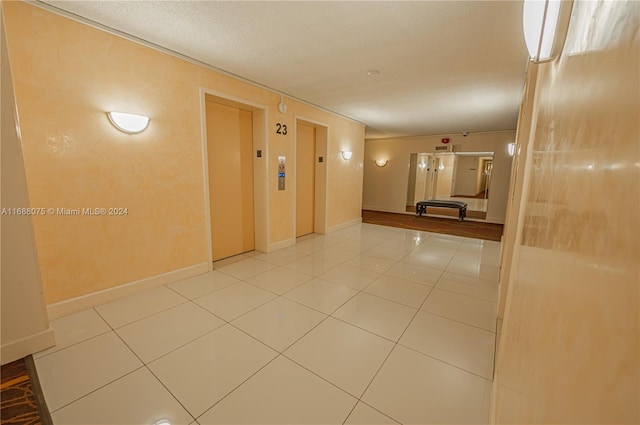 hallway with elevator and tile patterned flooring