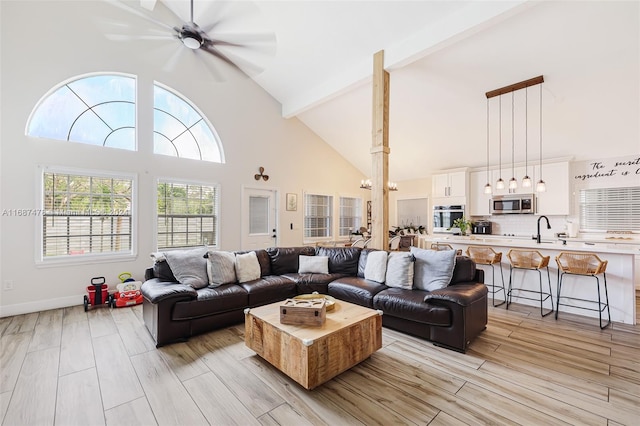 living room featuring high vaulted ceiling, sink, ceiling fan, and light hardwood / wood-style flooring