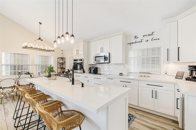 kitchen featuring white cabinetry, light wood-type flooring, appliances with stainless steel finishes, and an island with sink