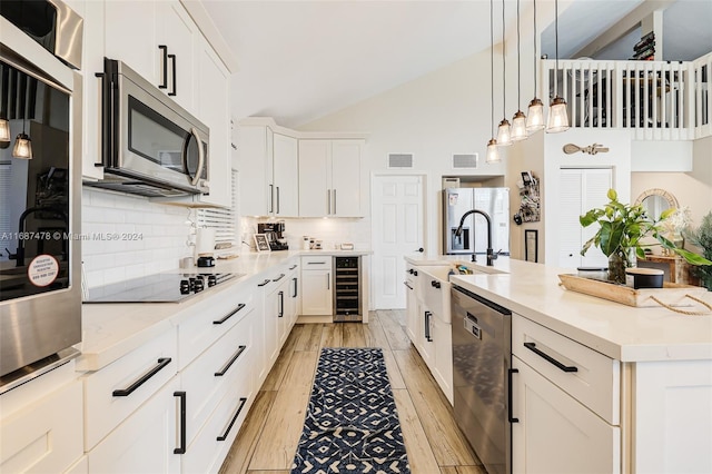 kitchen with a center island with sink, white cabinetry, light wood-type flooring, appliances with stainless steel finishes, and wine cooler