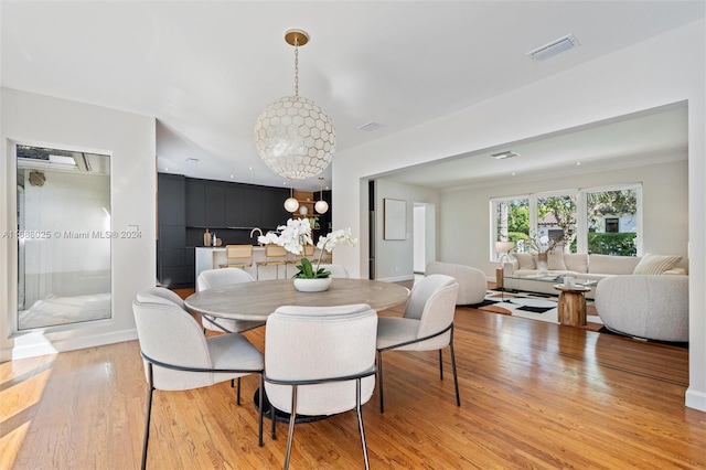 dining space with light wood-type flooring and a chandelier