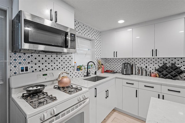 kitchen featuring white cabinets, decorative backsplash, sink, and gas range gas stove